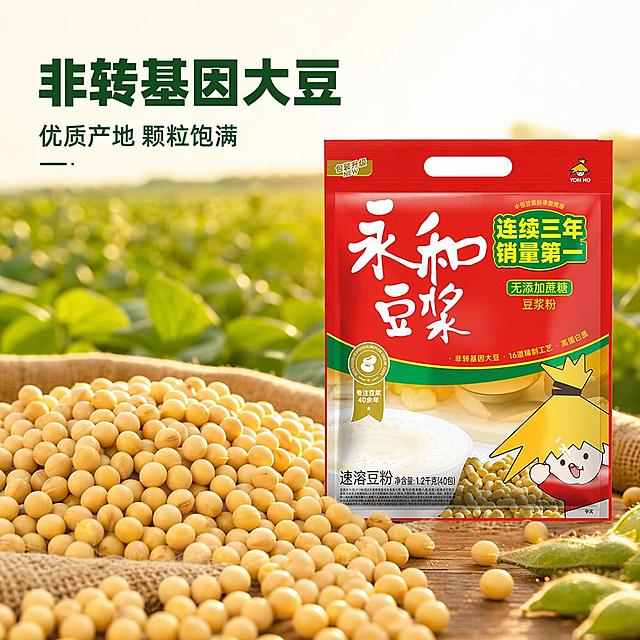 [主图-2] 永和豆浆粉原料溯源，非转基因大豆核心卖点图。
[氛围风格] 自然原生，健康真实产地氛围感；
[画质] 商业摄影质感，光线柔和通透，产品清晰真实，画面干净高级。
[元素] 永和豆浆粉包装放置在画面右侧三分之一处，左侧主体是一大片饱满干净的东北黄豆，颗粒均匀金黄透亮，背景虚化一片绿色豆田，阳光透过豆叶洒下斑驳光影，保持豆浆粉包装袋外观、颜色、结构和原图完全一致，无变形色差。商品主体占比控制在60%-70%之间，层次分明，包装和原料都清晰展示。
[光影] 自然暖阳逆光，从豆田后方照射过来，给大豆和包装袋边缘镶上柔和金边，突出大豆的通透颗粒感，整体光影温暖自然，还原真实产地日照氛围。
[配色] 主色调大豆金黄+豆田嫩绿，搭配包装红色形成舒适对比，整体自然清新，突出原料优质感。
[视角构图] 略带俯视角度，前景大豆+中景包装+远景豆田，景深效果突出主体，自然层次拉开距离。
[文字版式] 画面左上负空间，主文案「非转基因大豆」使用深绿色粗体大字，下方小字标注「优质产地 颗粒饱满」，字体清爽无衬线，文字不遮挡主体，保持清晰对比。
[输出要求] 1:1比例，文字清晰锐利，超高清商业摄影质感，宽度2048px，高度2048px。
[负向提示词] 变形，文字错乱，产品图模糊，背景杂乱，水印，电商平台Logo，颜色失真，产品变形，文字遮挡主体。