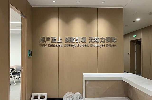 在墙面设计“用户至上 战略引领 元动力保障 
User Centered, Strategy Guided, Employee Driven ”金属立体字，占背景宽一半大小，中文字大些