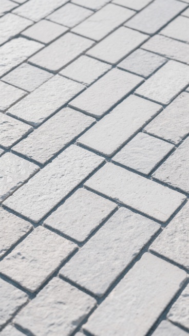 浅灰色调的石材铺地纹理，由大小不一的长方形石砖以垂直交错的方式整齐排列，砖缝为深灰色细线，石砖表面带有自然的细微粗糙质感，整体呈现出规则的几何图案，营造出简洁、稳重且具有工业风的铺装效果，光线均匀柔和，无明显阴影，纹理可无缝拼接。预览效果