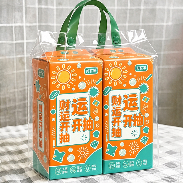将第一张白底图中悬挂式面巾纸包装的全部图案主题（橙青撞色、太阳、星星、钻石、几何图形、“财运开抽”大字、“好忆家”品牌标识等所有装饰元素和文字）完整迁移到本图中两提面巾纸的包装上，保持透明手提袋、绿色提手、格子桌布背景、包装摆放角度和整体构图不变，包装图案贴合原包装的透视角度和立体感，图案完整清晰，光影自然真实，透过透明袋可见的包装侧面图案也要对应迁移，产品摄影质感