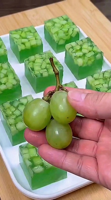 将棋盘格案板替换为统一的浅色纯木浆色纯色案板，保留原画面整体色调和光线不变，保留手、青提和放水晶糕的盘子所有内容不做任何改变预览效果