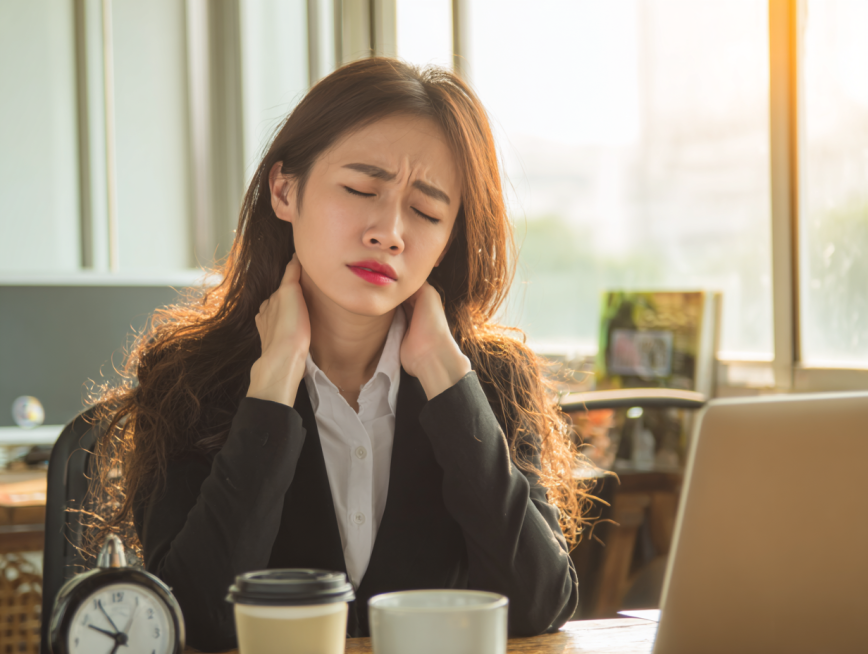 A young Asian female professional in office wear, massaging her neck with a pained and exhausted exp预览效果