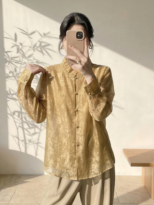 保持人物姿势、身材比例、脸型发型和背景不变，仅将人物身上的白色衬衫替换为图片中的芥末金色提花新中式衬衫，保留这件金色衬衫的所有细节：木耳边立领、金色盘扣、金丝提花纹理、通透的纱质面料和版型，适配人物身预览效果