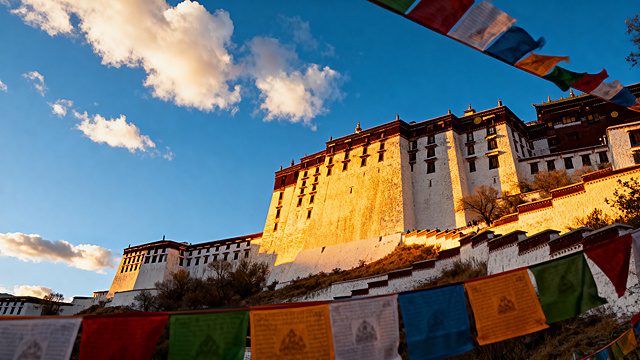 西藏布达拉宫全景，金色夕阳照射在白色宫墙上，天空是澄澈的蓝天白云，前景有五彩经幡随风飘扬，专业旅行摄影风格，画面通透自然，光影层次丰富，超高清画质