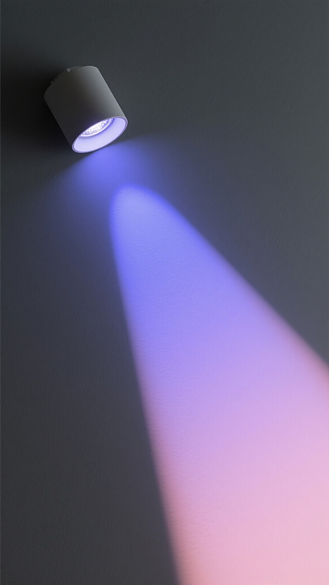 一个位于画面左上角的现代简约风格筒灯，发出柔和且带有明显光束层次感的彩色光效，主色调为梦幻蓝紫色渐变，光线从灯源向下呈45度角倾斜延伸，光束边缘带有轻微的粉色光晕，在深灰色的背景上形成清晰而富有立体感的光影投射，整体氛围神秘而宁静，灯光效果具有透明感和细腻的渐变过渡，无任何文字或装饰元素干扰纯粹的光影呈现。