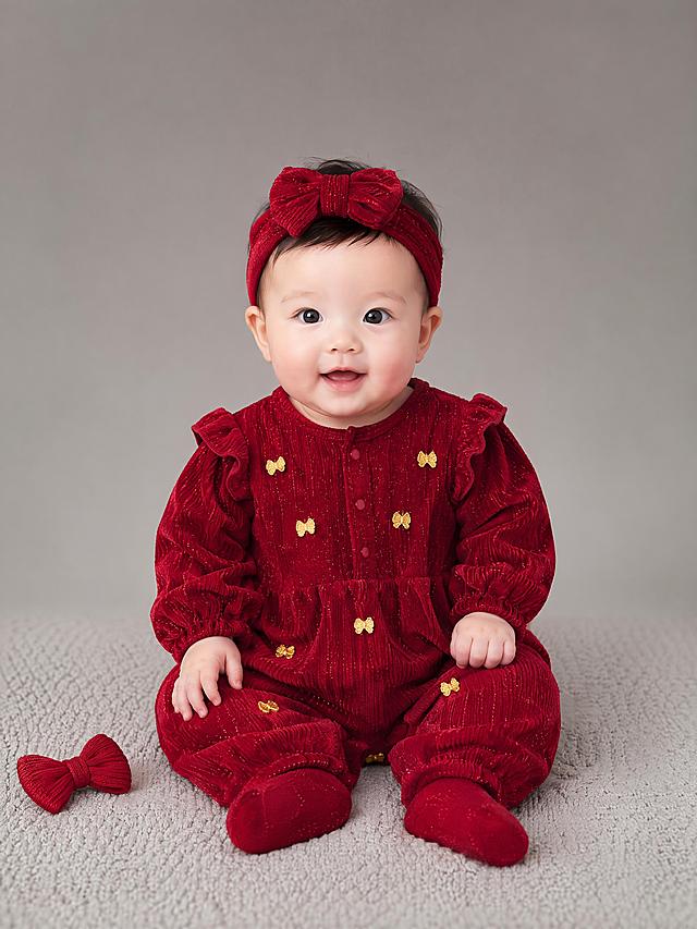 超写实百天宝宝模特室内影棚服装展示摄影。
主体：百天宝宝红色连体衣严格参照上传产品图，完整保留酒红色细闪灯芯绒、金色小蝴蝶结刺绣、荷叶飞边全部细节，纹理、颜色、造型与原图完全一致，产品占画面 50%，核心展示面完整不裁切，全身构图，保证衣服和人物脸部都清晰，不失真。
呈现模式：C2 全身模特
构图与使用状态：自然坐姿，正面平视机位，中国百天女宝宝穿着这件红色连体衣，模特眼睛不要打马赛克，完整清晰露出眼睛。
风格：可爱精致高级影棚
场景概念：纯色简约儿童摄影影棚，浅暖灰色渐变背景。
承载与陪衬：①宝宝坐在浅灰色针织摄影垫上；②身侧放一个小小的红色针织蝴蝶结道具；③背景干净无多余杂物，突出服装主体。
配色 / 材质：酒红色/金色/浅灰色；细闪灯芯绒面料/针织摄影垫/布艺道具。
光影：影棚专业柔光正面打光，均匀明亮，清晰呈现灯芯绒肌理和金色刺绣细节，阴影柔和，服装和脸部都清晰，没有过曝和模糊，整体高级喜庆，适合节日氛围。
严格要求：衣服和人物脸部都必须清晰可辨，不能失真模糊，模特眼睛完整清晰不打码。
参数：4K 写实。严格锁定宽高比为 3:4。