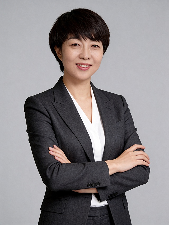 参考第一张图保留人物脸型､年龄等特征生成职场形象照,参考第二张图人物占位和比例,标准焦段50mm,F/4光圈(F/2.8-F/4区间),平视视角(镜头与人物视线齐平);人物占画面70%,人物居中(居中构图),位于画面中心,为视觉聚焦点,入境范围头部及以下至臀部下方10cm(半身像);左右留少量背景空间;头部与画面顶部保留5%空间;头部发型完整;头肩比例协调,主体锐利,美颜磨皮韩式精致自然的浓妆,均匀肤色提亮肤色,外穿V领深灰色西装外套(偏暗),内搭白色V领衬衫;深灰色西裤(偏暗);发质柔顺光泽;双臂交叉于胸前,姿态舒展,传递出自信从容的气场.表情自然,干练;微笑;画质清晰,头部完整,高清棚拍专业摄影人像写真,均匀肤色,头部完整,结构准确;光比1:1.5,4800K中性光,修饰脸型,肤质哑光细腻,面部微微雾面柔光,轻透裸肌感,真实毛孔纹理,32K画质,去除人物之外的所有元素,零噪点降噪,极简中灰度(偏冷)纯色背景｡