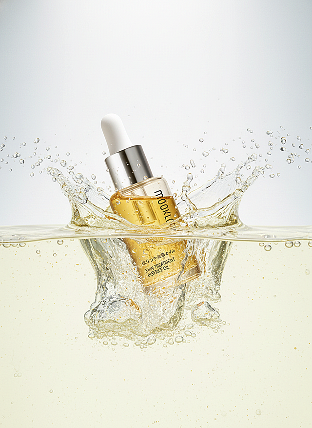 主体坠入淡黄色背景的水中，激起大量水花与气泡，整体呈现出灵动、富有活力的质感，采用写实的产品摄影风格。