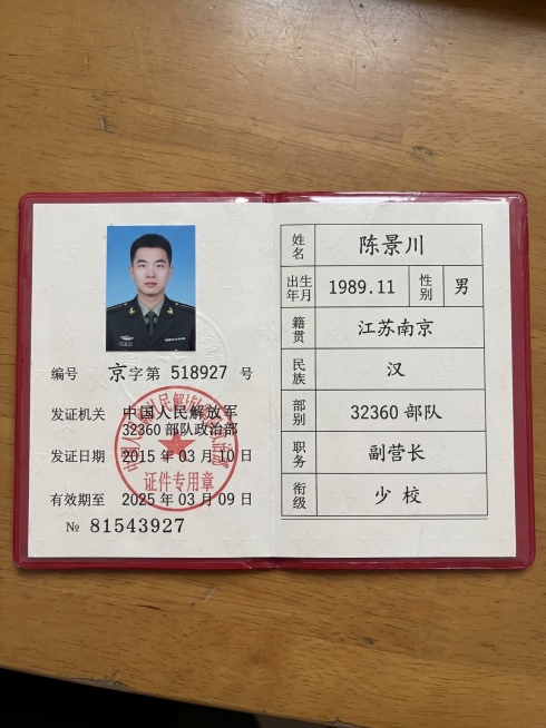 参考这张证件照片模板，生成新的军官证件照片，照片平躺放在实木书桌上，俯拍视角，柔光漫反射侧光，画面清晰真实。保留原版式布局，替换所有文字信息，文字使用打印体，具体信息为：姓名：陈景川 出生年月：198预览效果