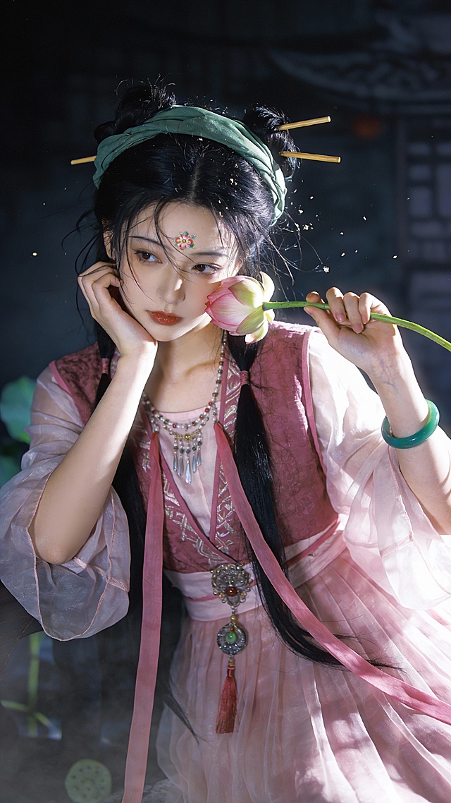 摄影作品，古风女子，，乱发用绿色发巾包裹，两支筷子发叉，青绿色的战国袍衣裙，简单的挽发，手拿一朵小荷花在轻嗅。另一只手托腮，慵懒的样子，高清画质。，胶片摄影，镜头语言，淡彩，暗调，人物是一位美少女，容颜俊美，唐朝女生有着白皙冷白皮，皮肤光滑透亮。她散黑色的长发，气质妖冶又羞涩。 光影突出主体，背景唯美，古装美女，肢体动作有张力，国色天香，进行半身特写，清冷色调，高颜值，既视感，情绪氛围感拉满，透视感，暗朦，光朦，胶片颗粒质感，层次丰富，写意，朦胧美学，光的美学，lomo效果，高级感，杰作，皮肤白皙干净光滑水润细腻清透。极致超清，插画，厚涂，气质温柔，oc渲染，超高清画质，细节丰富，精致感强，极致超清，极致细节，氛围感，眼睛狭长眼尾上挑，干净光滑的画面风格，呈现出极致清晰的光滑镜面质感画风。32K像素点压缩处理致所有细节都清晰展现。虚拟背景 古风 美人 穿着淡粉色纱衣，外面穿着深粉色的马甲纱裙 额前碎发零散飘逸 腰佩吊坠，颈戴璎珞流苏，手腕上戴着一个翠绿镯子， 头发弄了一个双丫髻，及腰飘逸的长发，还弄了粉色丝带垂落在胸前 粉色发带，额头还弄了花钿。真人，冷白皮，肌肤似雪 超级细腻 超级细节 超高清