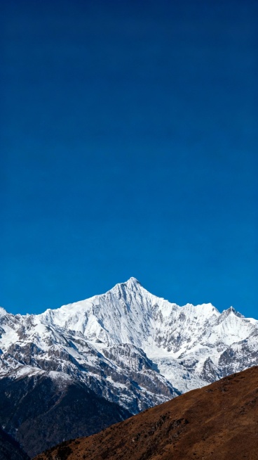 以蓝天为底，搭配巍峨的雪山与棕褐色山体，画面干净且有视觉冲击力，营造出清冷，舒展的氛围，深蓝色调，天空占画面的上面三分之二。预览效果