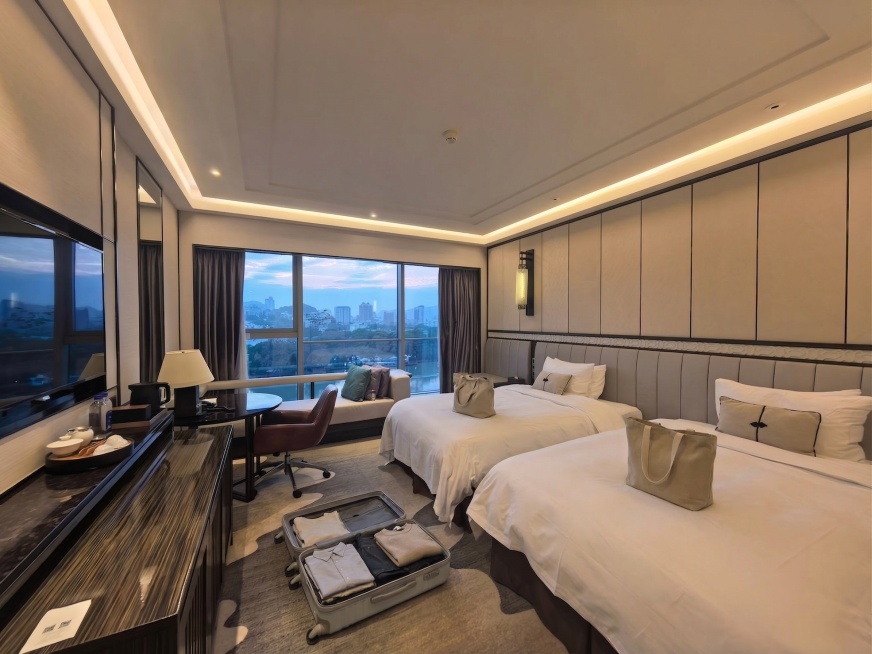 在两张床靠近枕头的位置各放置一个米色帆布购物袋，自然靠放；在两张床前方的地毯空白位置放置一个打开的浅灰色行李箱，箱内放置少量衣物，摆放自然合理，不遮挡电视柜和桌椅。保持原图整体新中式江景双床酒店结构、预览效果