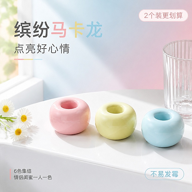 [单张主图] 陶瓷牙刷座，高级氛围感主图，推广马卡龙配色陶瓷牙刷座。
[参考比对] 保留原产品圆形圆润造型和马卡龙色系陶瓷质感，仅更换场景背景并添加合规文案排版。
[画面主体] 三个不同颜色（粉色、浅黄色、浅蓝色）的圆形陶瓷牙刷座整齐排列在白色洗手台台面，产品外观、圆润造型、陶瓷材质、马卡龙色系与输入产品图保持绝对一致，杜绝任何变形和色差，精细化处理陶瓷釉面高光和光滑质感。商品主体占画面约50%，居中放置。右侧放置透明漱口杯，左侧点缀三朵小雏菊作为装饰。
[构图版式] 采用左文右物场景型，左侧大面积留白放置文案，产品放右侧放大展示，底部以白色洗手台承托。
[场景元素] 背景为现代明亮浴室，浅蓝色淡粉色渐变背景墙，充足阳光从左侧窗户斜射进来，整体空间干净通透，呈现现代简约卫浴风格。留有足够的文字排版空间，构图简洁不杂乱。
[文案版式] 左上负空间左对齐留安全边距：
第一行大字："缤纷马卡龙"
第二行小字："点亮好心情"
左下角放置两行小号文案："6色集结"
"情侣闺蜜一人一色"
右上角圆角角标："2个装更划算"
右下角圆角角标："不易发霉"
文字颜色从牙刷座颜色提取，浅色背景深色字，保证清晰可读，不遮挡产品主体。
[光影质感] 主光为左侧自然斜射窗光，光线柔和充足，在台面形成浅淡投影，辅光为墙面反射补光，陶瓷釉面有自然柔和高光，整体通透干净，高调摄影风格，景深适中，背景轻微虚化。
[配色字体] 主色调为马卡龙浅色系，背景浅蓝淡粉渐变，文字采用深灰和对应产品色对比，字体选择轻无衬线，主标题最大，副标题次之，角标最小，层级清晰。
[比例分辨率] 1:1 比例，2048px × 2048px，2k分辨率，文字清晰可辨，超高清画质。
[负向提示词] 变形，文字错乱，产品图模糊，背景杂乱，水印，电商平台Logo，错字，遮挡主体，畸形产品，色差