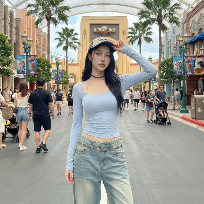 将背景替换为环球影城内部场景，保持模特和服饰不变，更换为单手扶帽的姿势预览效果