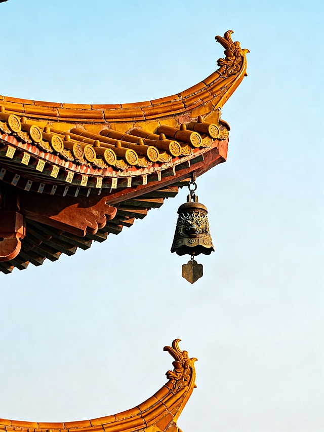 帮我生成中国建筑屋顶一角的图片，建筑屋顶类似于黄鹤楼，尖角出悬挂东方特色的古物件风铃，背景不灰暗，比例3:4