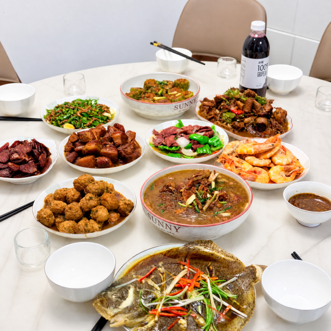 优化这张团圆饭菜品图，让整体画面变得干净通透，提升色彩饱和度和食物光泽感，让菜品看起来更有食欲，矫正轻微透视畸变，保留所有菜品、餐具和葡萄汁饮料布局位置不变，整体风格高级干净，提升画质，让食物颜色更自预览效果