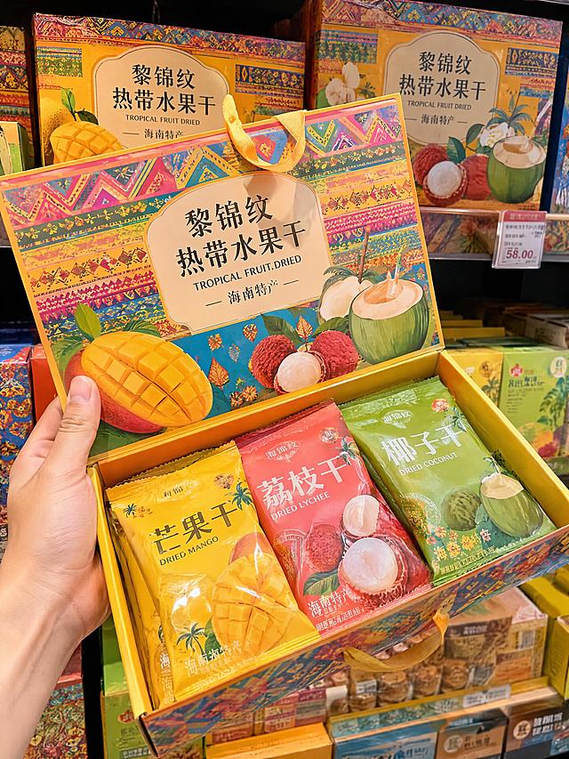 黎锦纹热带水果干礼盒，海南特产店货架斜放实拍，手提开盖露出独立包装果干，芒果黄荔枝红椰青绿多巴胺撞色，明亮吸睛