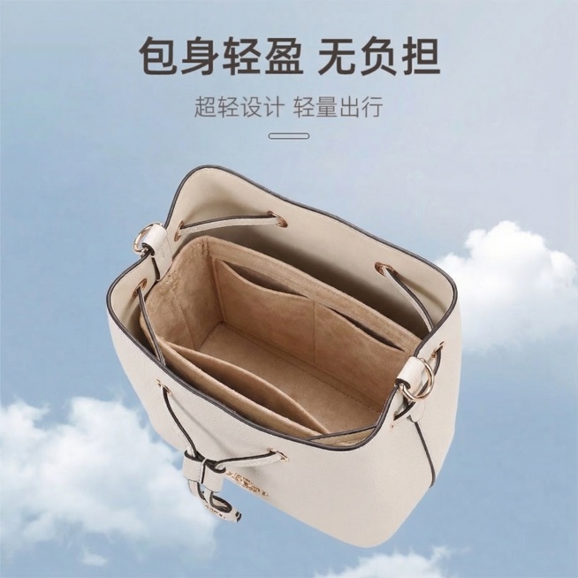淘宝商品主图，产品是米色绒面蔻驰Rowan22水桶包专用内胆包，展示内胆包放置在包包内的整体效果，卖点超轻设计轻盈无负担，风格简约干净高级品质感，背景为浅蓝渐变带白色云朵氛围，柔和自然光影，整体干净明预览效果