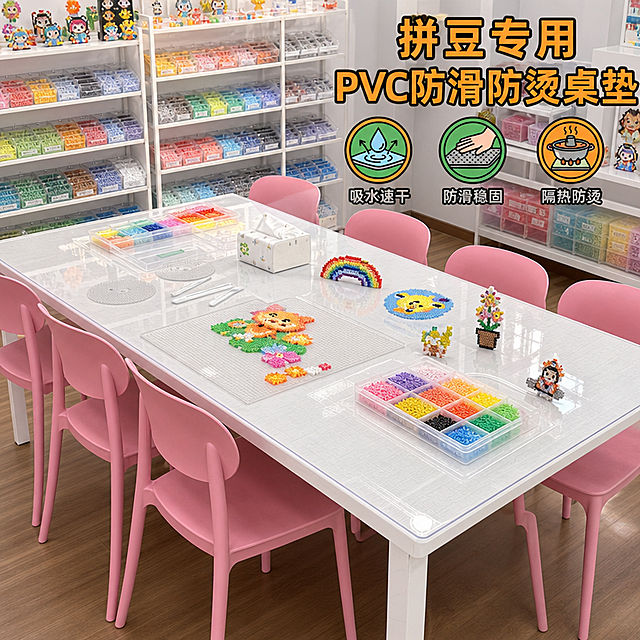 拼豆手工坊桌垫使用场景图，斜侧角度拍摄白色长桌，铺着透明PVC防滑防烫桌垫，多把粉色椅子围绕，背景整齐排列的拼豆收纳架色彩丰富，桌上摆放拼豆作品和工具，明亮整洁的商业空间，电商宣传图风格