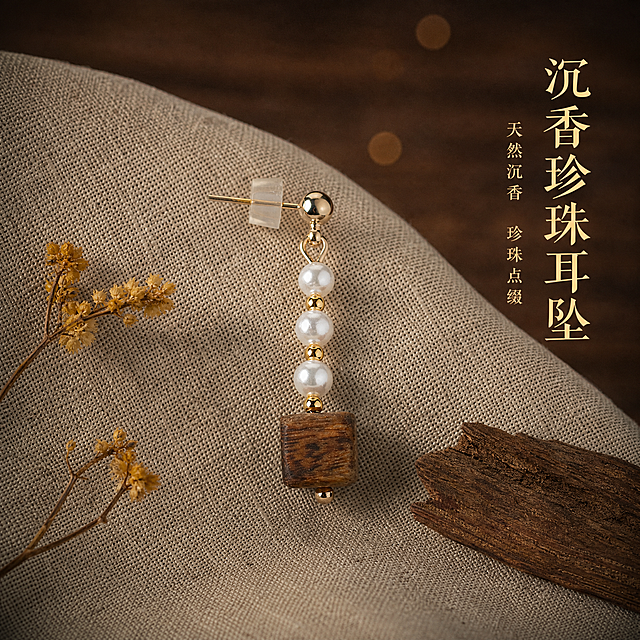 新中式高级珠宝暗调摄影风格主图。沉香木珍珠耳坠放置在浅色粗麻布上，麻布纹理清晰自然，耳坠呈斜向摆放，完整展示从耳钉到沉香木珠的全部结构。沉香方木珠表面有清晰的深棕色油脂线纹理，纹理与原图完全一致，珍珠圆润有光泽，金色配件细腻。产品外观与沉香纹理均与原图完全一致，沉香纹理必须清晰保留。旁边放着一小枝干枯的黄色小花和一片沉香木片作点缀。背景是深胡桃木台面虚化，暖棕色散景光斑。暖黄色柔和侧光从上方打亮，珍珠温润光泽，木珠纹理细腻，金色配件有淡淡反光。右上文字竖排：大字"沉香珍珠耳坠"暖金色宋体，小字"天然沉香 珍珠点缀"。整体色调暖米棕，暗调高级，质感温润。1:1正方形构图，2K超高清。