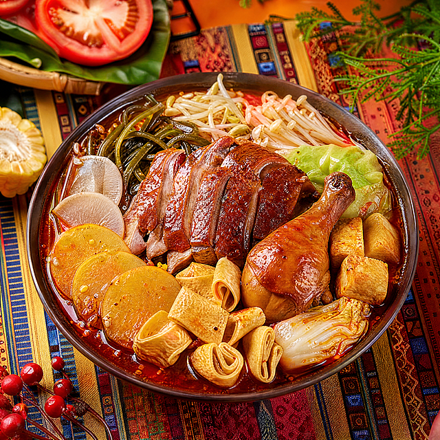 8K超写实美食摄影，正方形构图，一碗丰盛的红汤冒菜，食材包含卤鸡腿、烤鸭片、豆泡、面筋、豆皮、绿豆芽、海带丝、包心菜、金针菇、萝卜、土豆、娃娃菜，卤鸡腿和烤鸭片作为主要荤食摆放在视觉中心位置，鸡腿卤香浓郁色泽棕红，烤鸭片皮脆肉嫩纹理清晰，每样食材都有真实清晰的纹理细节，红汤呈油亮飞溅效果，汤汁油润光泽感强，背景为民族风彩色编织餐布与暖橙色桌面风格，色彩高级自然，拒绝过度饱和，专业美食打光，细节拉满，质感真实