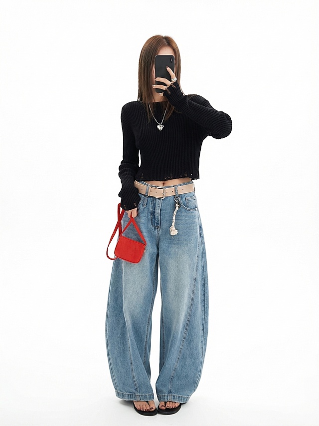 产品精修，展示这套黑色短款针织毛衣和浅蓝色阔腿牛仔裤，放置在纯净的纯白背景上。3D立体展示，空气感填充，增强衣服体积感，自然垂坠，拒绝扁平化。商业蒸汽熨烫处理，去除褶皱，面料纹理清晰，边缘厚度可见。保留包包挂件等所有配饰细节，使用明亮专业棚拍光，生成真实光影。保留模特肢体展示穿着效果，禁止改变原有服装结构和配色。