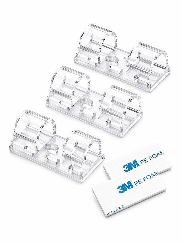 [主图-1] Clear Cable Clips with Strong Adhesive 首图白底产品展示。
[统一基调] 亚马逊跨境极简风格，纯白背景，产品居中，无任何文字、边框、水印、道具或装饰元素，干净克制，突出产品本身。
[画面] 透明亚克力材质的自粘式理线夹作为绝对主体，占画面约85%以上，正面45°微俯视角度完整展示产品外观。画面中包含3-4个透明理线夹整齐排列，清晰呈现其透明卡扣结构、长方形底座和双卡槽设计，产品材质为高透亚克力，边缘光滑有光泽。旁边自然放置1-2片带蓝色3M PE FOAM字样的白色背胶贴片，背胶与理线夹分离摆放，展示配件关系。产品底部有轻微接触阴影，不悬浮。
[光影质感] 专业影棚商业摄影质感，主光从左上方45°打下，光线柔和均匀，透明材质有清晰的高光边缘和内部折射效果，亚克力通透感强，背胶贴纸有纸质哑光质感，阴影浅淡自然。
[配色] 纯白背景，透明无色产品主体，点缀背胶上的蓝色3M标识色，整体干净明亮。
[文字版式] 首图无任何文字、标题、标签或图形元素，完全符合Amazon首图白底规范。
[输出要求] 比例3:4，产品清晰锐利，材质真实，无变形、错字、模糊、杂乱、水印、平台Logo、多余边框。