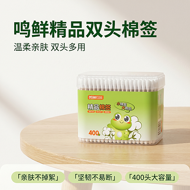[主图 1] 鸣鲜400头精品双头棉签产品首图，干净治愈家居风。
[氛围风格] 清新治愈明亮干净的家居氛围，浅原木温馨质感。
[画质] 商业摄影质感，光线柔和通透，产品清晰真实，画面干净高级。
[元素] 透明盒装棉签产品居中放置，摆放在浅原木色桌面上，背景为干净的浅奶白色墙面，左上角预留文字负空间，商品主体占比约70%，保持产品外观包装、颜色、结构和输入产品图完全一致，杜绝变形和色差，画面满屏无边框。
[光影] 柔和自然光从左侧射入，均匀照亮产品，整体光线明亮通透，阴影过渡自然柔和，突出产品干净质感。
[配色] 主色调为浅原木色+奶白色+绿色，和包装风格统一，清新舒适。
[视角构图] 平视拍摄，景深适中，产品完整居中，轮廓完整不裁切。
[文字版式] 左上负空间左对齐留安全边距，大字主文案"鸣鲜 精品双头棉签"深绿色粗体最大号；下方小字文案"温柔亲肤 双头多用"绿色小号；底部横向排列三个卖点标签，每标签内为简短文字：「亲肤不掉絮」「坚韧不易断」「400头大容量」，浅绿底深字。文字清晰不遮挡产品。
[比例分辨率] 1:1比例，2k分辨率，文字清晰可辨，超高清。
[负向提示词] 变形，水印，文字错乱，产品图模糊，背景杂乱，配色刺眼，遮挡主体