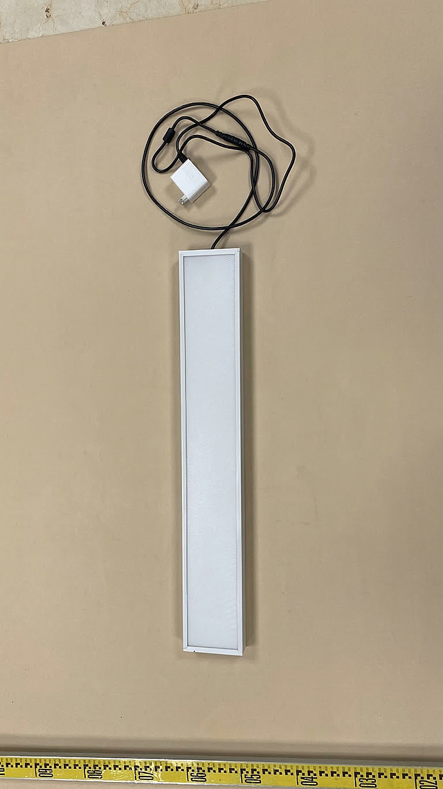 将图片的背景替换为干净的米色，保留主体长条形灯具、充电器、黑色电线和底部黄色标尺不变，画面自然真实