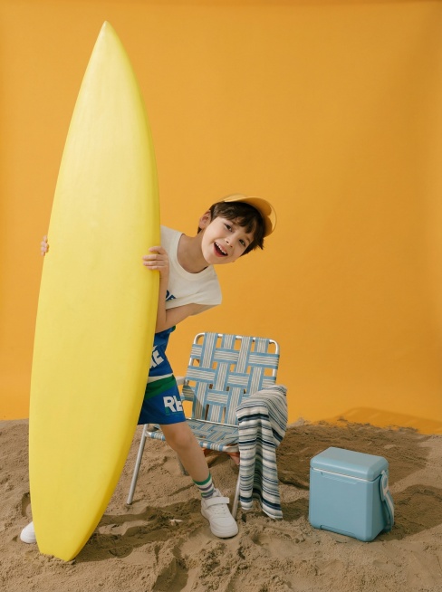 将小男孩融入场景，躲在冲浪板后，补全画面预览效果