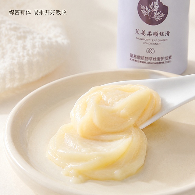 [主图-3] 发膜质地与肤感展示
[氛围风格] 家居治愈风，干净通透；
[画质] 商业摄影质感，极致微距细节清晰，画面干净高级。
[元素] 勺子舀出一勺艾姜发膜，放置在浅色陶瓷盘上，极致微距展示发膜细腻绵密的膏体质感，产品瓶身在背景虚化突出。保持产品外观、物理结构、材质质感、颜色与输入产品图绝对一致，杜绝任何变形和色差，精细化处理。
[光影] 柔光箱打光，膏体质感清晰，高光自然，细节锐利。
[配色] 浅米白背景，膏体浅米黄色调，整体干净明亮。
[视角构图] 俯视微距特写，聚焦膏体质地。
[文字版式] 左上角小字标注"绵密膏体 易推开好吸收"，字体纤细不抢主体。
[输出要求] 1:1比例，文字清晰可辨，超高清商业摄影质感。
[负向提示词] 变形，文字错乱，产品图模糊，背景杂乱，水印，电商平台Logo。