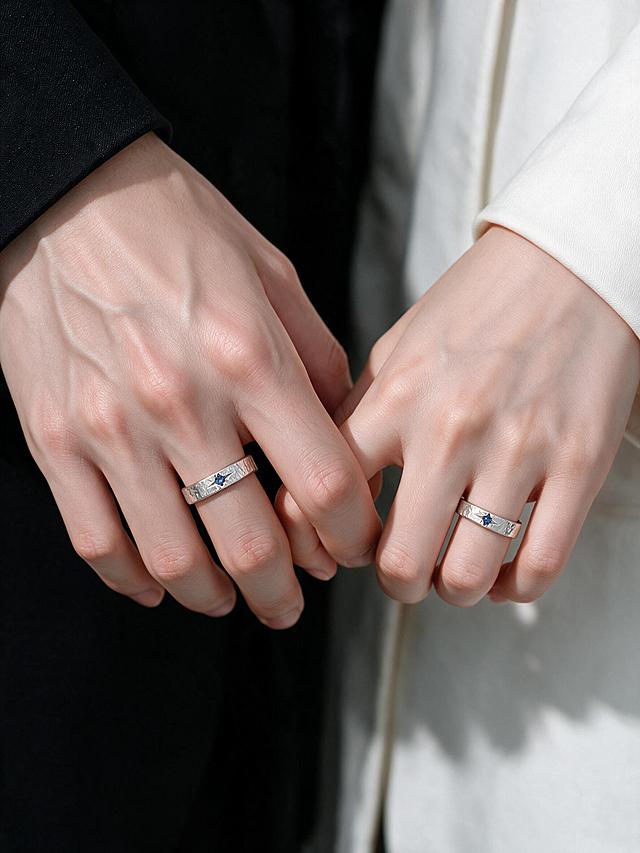 参考图手部骨骼、皮肤纹理细节完全保留，保留男士骨感大手，女士纤细白皙小手，保留黑色西装袖口、米白色西装袖口，服装面料质感不变，戒指款式完全不变（锤纹肌理蓝色星钻银戒）。修改手部姿势为：男生和女生的小拇指互相勾住（拉钩姿势），其他手指自然弯曲，戒指正面清晰展示。半身手部特写，竖版9:12，商业珠宝氛围感，皮肤质感真实细腻，原图光影色调保持不变，高清8K，细节丰富，电商详情页实拍风格，柔和室内自然光，干净高级情侣饰品摄影