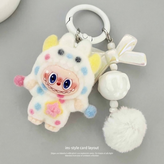 将毛绒挂件手作主体自然融入ins风统一背景中，白色挂件颜色保持白蓝粉不变，所有挂件原有颜色完全保留，保持挂件主体物理结构和细节完全不变。
光影匹配：背景光源从左上方来，在挂件右下方生成柔和自然的投影，预览效果