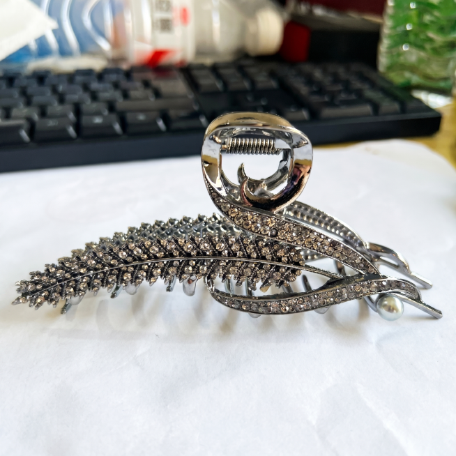 产品精修，保留原图背景，大幅提升发夹整体亮度，强化枪黑色金属光泽和水钻的通透闪耀感，让枪黑金属部分更亮泽，透明水钻更闪亮通透，珍珠部分更莹润，消除画面灰暗感，保持商品所有结构细节完整，画质超清锐利，4预览效果