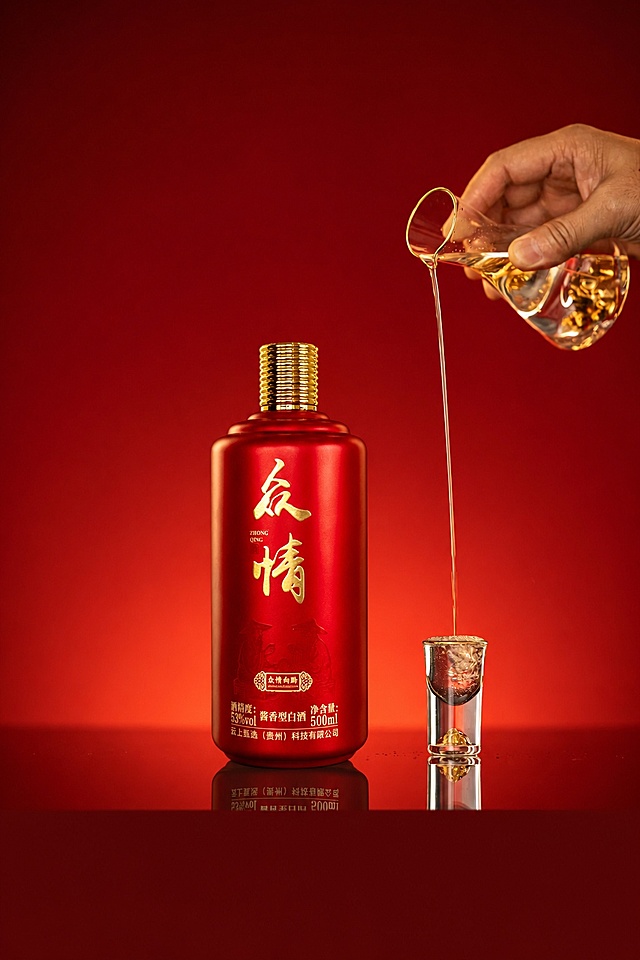 参考图1的光影、构图和整体结构，保留原场景中倒酒的手、分酒器、酒杯和红色背景，将图1的酒瓶替换为图2的红色众情酒瓶，保持整体光影、构图、色调和元素位置不变