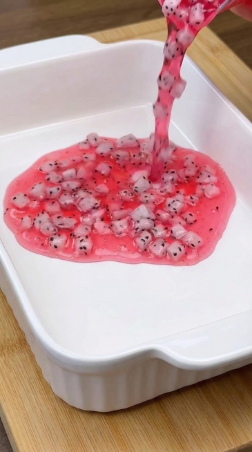 参考原图，9:16比例，保持整体画面构图、白色烤盘、正在倒入的粉色带火龙果粒液体完全不变。去除顶部状态栏和底部文字、进度条，仅保留美食画面。把棋盘格砧板换成浅原木色木质砧板，带有自然清晰木纹，风格简洁预览效果