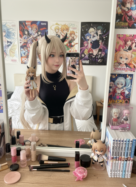 cosplayer真人照片，根据该图生成一张现实生活中扮演该角色的写实风格，人物所在的写实场景与原作相对应，人物一只手抬起拿着手机对着镜子正在自拍，另一只手靠近镜头托着带有与该cosplayer照片相预览效果