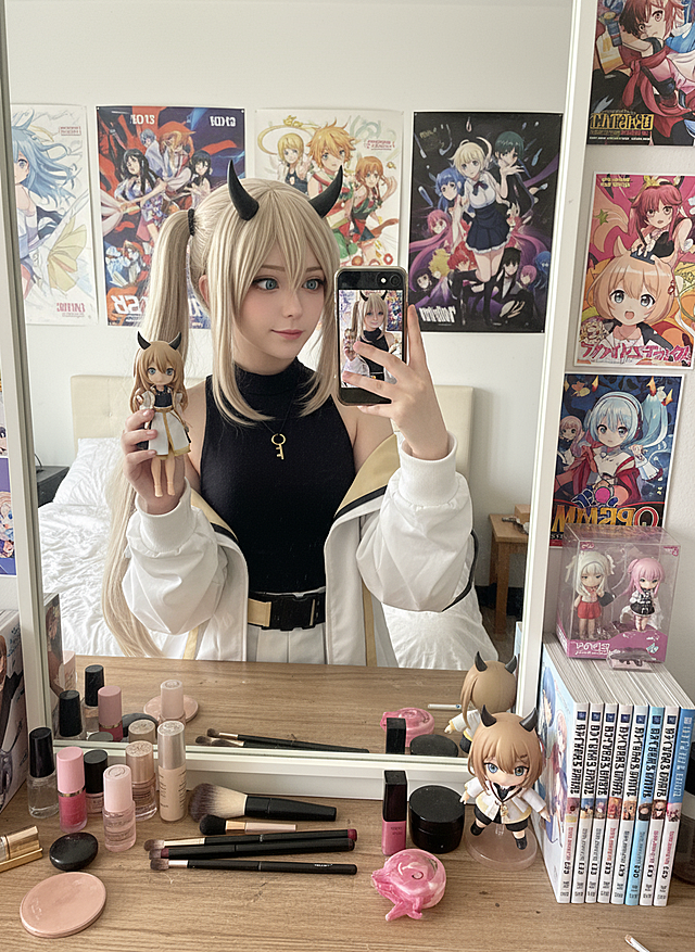 cosplayer真人照片，根据该图生成一张现实生活中扮演该角色的写实风格，人物所在的写实场景与原作相对应，人物一只手抬起拿着手机对着镜子正在自拍，另一只手靠近镜头托着带有与该cosplayer照片相对应的玩偶手办。
