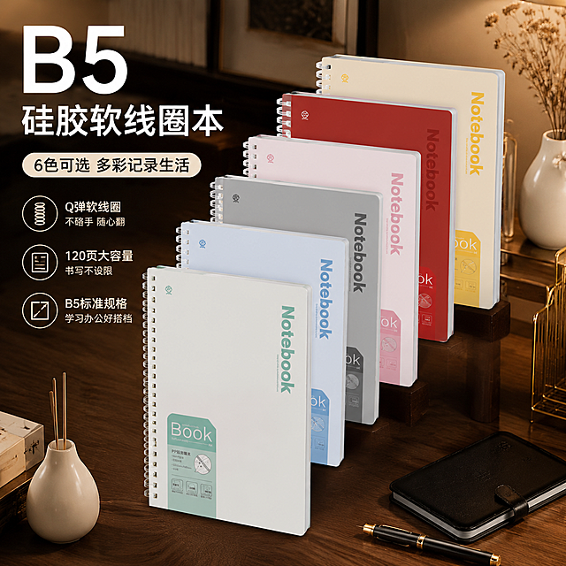 天猫直通车主图，轻奢高级感书房桌面场景，柔和暖光营造氛围感，深胡桃木色桌面搭配黄铜金属书立、黑色皮质笔记本和白色陶瓷花瓶干花，画面中央阶梯式展示6本不同颜色（雾松绿、冰川蓝、石墨灰、桃雾粉、烈焰红、柠檬黄）的B5硅胶软线圈笔记本，由低到高排列有层次感，硅胶软线圈通透Q弹质感清晰，笔记本封面平整挺括不变形，突出软线圈不硌手、6色可选、B5规格、120页大容量核心卖点，整体画面轻奢高级，色调沉稳有质感，电商主图视觉冲击力强，专业商业产品摄影