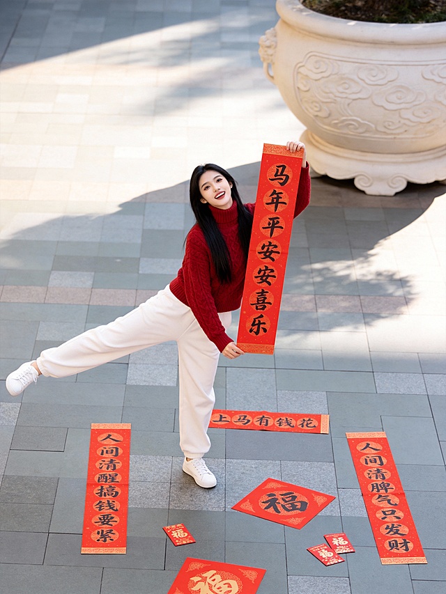 国潮风实景拍摄，红白配色凸显喜庆感，剪纸风春联与大字书法结合，传递中式年味，人物动态自然，节日氛围浓厚。