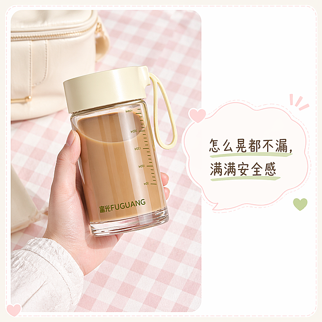 严格还原富光玻璃杯产品细节，包含透明杯身、米白色杯盖、黄色提绳、杯身刻度线、杯底“富光FUGUANG”LOGO位置与字体，保持所有细节和质感不变。画面比例为1:1竖版，INS风少女感清新电商主图，低饱和莫兰迪配色，明亮柔和顶光，背景为粉白格纹，画面为白色边框场景图，左侧为手持富光玻璃杯（杯身装棕色饮品），杯身正面“FUGUANG”LOGO清晰可见，背景搭配米白色包包，右侧对话框标注“怎么晃都不漏，满满安全感”，整体排版为“左场景 + 右对话框”，留白充足，整体风格清新治愈。场景图边框、对话框样式、文字字体符合描述，产品手持角度自然。