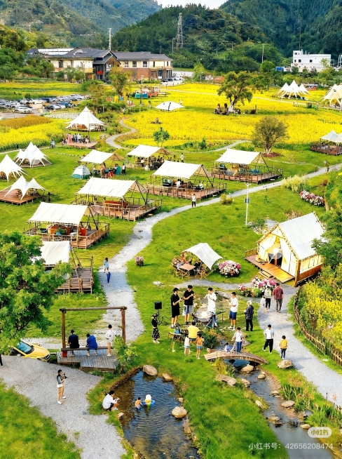 生成一张和参考图风格布局相似的山间露营营地，包含大片绿色草坪、多个白色露营天幕帐篷，蜿蜒小溪穿过营地，远处有黄色花田和休闲农庄建筑，背景是郁郁葱葱的山林，整体氛围自然休闲，高清写实风格预览效果