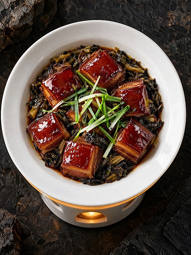 基于参考图中的红烧肉菜品，生成正俯视（90度俯拍）角度的美食摄影图，保持红烧肉色泽红亮油润、方块整齐，梅干菜点缀，顶部撒葱叶装饰，白色宽边瓷碗装盛，下方白色加热炉带烛光，深色岩石质感背景，暗调专业美食摄影，高清细节，诱人食欲