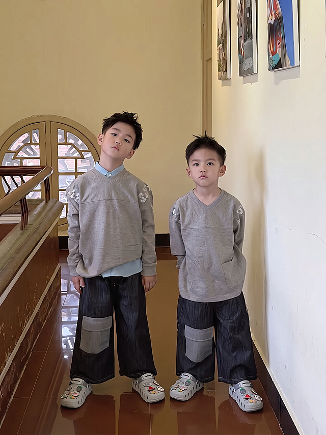 保留原图片的人物、服装、背景和所有其他内容不变，只将图中两个小孩脚上现有的鞋子替换成第二张图片中的灰色汤姆猫系列洞洞鞋，鞋子位置和大小适配脚型，整体自然协调。