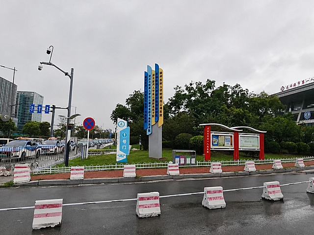 将图二的连云港市第一人民医院1号门精神堡垒导视牌，合成放置到图一红框标注的草坪位置，保留原图的整体环境和透视关系，为精神堡垒添加真实投影和立体感，让它看起来像是原本就放置在那里的一样