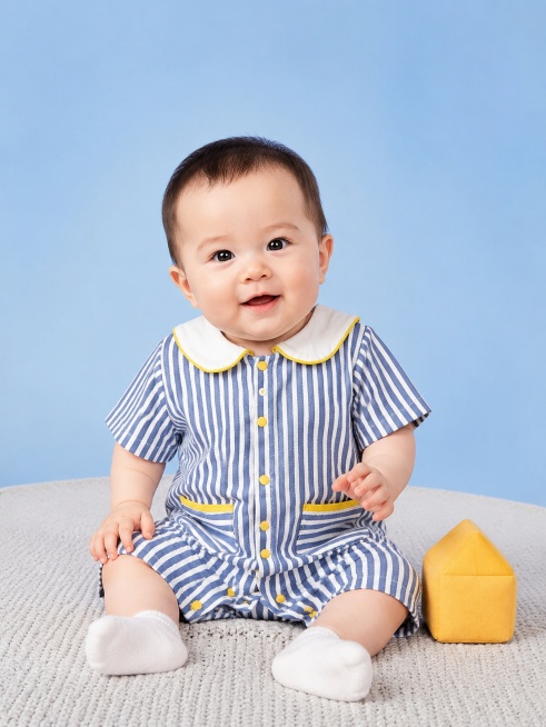 超写实百天宝宝模特室内影棚服装展示摄影。
主体：百天宝宝蓝白竖条纹连体衣严格参照上传产品图，完整保留蓝白竖条纹、白色翻领撞黄边、黄色纽扣、撞色口袋全部细节，纹理、颜色、造型与原图完全一致，产品占画面预览效果