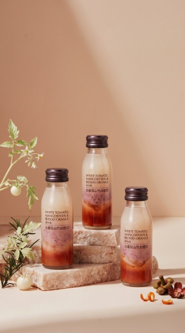 将原图场景中的三个护手霜产品替换成第二张图里的白番茄山竹血橙饮产品，保持原图场景、光影和构图不变，将装饰元素替换为白番茄，白番茄不要太明显，整体突出新产品为主，融合自然预览效果