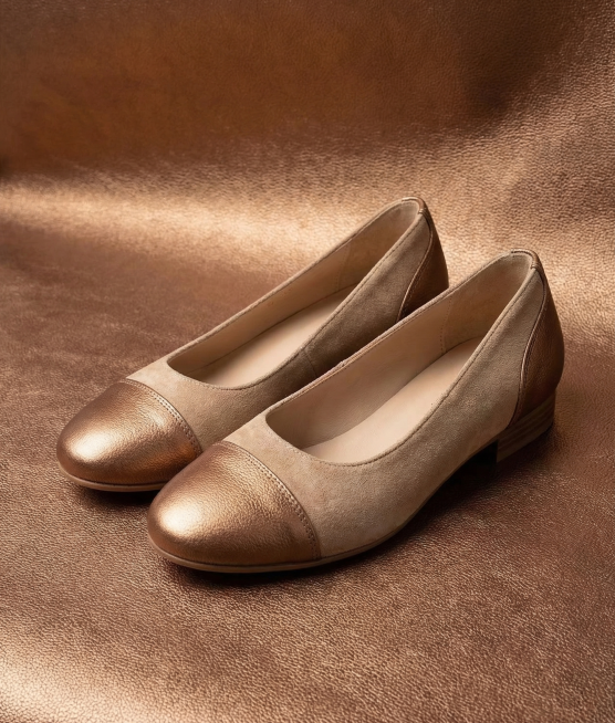 生成一双女童鞋子的产品场景图，鞋头和鞋尾使用参考图中的细腻皮革纹路材质，选择古铜金棕色皮革，鞋子主体搭配另外一种不同材质（如织物或翻毛皮），整体颜色不要单一，将这双女童鞋放置在相同的古铜金棕色皮革背景预览效果