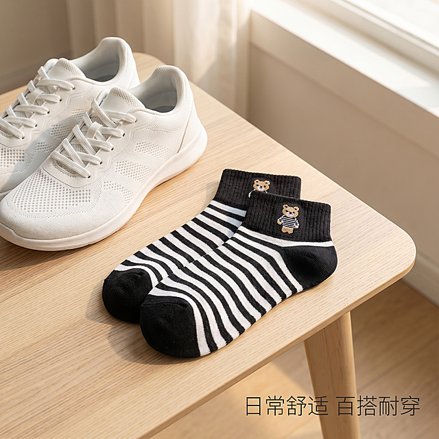 [主图 10] 整体场景氛围感图，传递简约运动生活态度。[氛围风格] 简约运动风，氛围感松弛感。[画质] 商业摄影质感、光线柔和通透、产品清晰真实、画面干净高级。[元素] 一双黑白小熊短袜随意摆放在运动鞋旁边，简约木质桌面背景，保持袜子外观（颜色、小熊刺绣图案、材质纹理）与输入产品图绝对一致，杜绝任何变形和色差，精细化处理。营造日常运动休闲氛围，商品主体占比约60%，画面满铺无边框。[光影] 柔和窗边自然光，氛围温暖舒适，光影自然。[配色] 木色背景搭配黑白袜子，简约自然舒适。[视角构图] 俯视偏对角构图，场景氛围感浓，景深适中。[文字版式] 右下角放置文字 "日常舒适 百搭耐穿" 深灰色细体文字，简洁不抢主体。[比例分辨率] 1:1 比例，2k 分辨率；文字清晰锐利，画面超高清。[负向提示词] 变形，水印，文字错乱，产品图模糊，背景杂乱，颜色失真，小熊图案变形