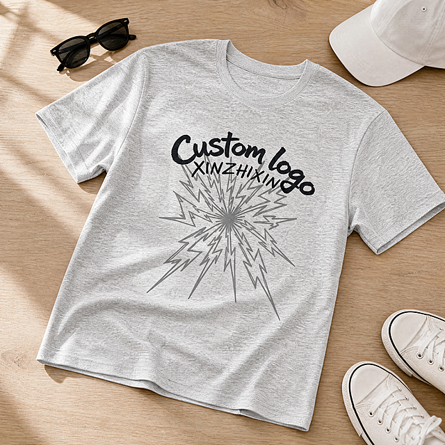[主图-5] 浅麻灰色Custom Logo T恤平铺细节展示图，含领口、袖口、下摆与面料细节，搭配极简生活场景。
[统一基调] 浅木色桌面背景，柔和自然光，高级生活方式静物摄影风格，极致细节超高清8K锐利对焦无噪点干净画面。
[画面] 浅麻灰色圆领短袖T恤平整铺在浅木色桌面上，略微倾斜的角度增加动感；T恤周围简约搭配一副黑色太阳镜、一顶白色棒球帽和一双白色低帮帆布鞋，营造日常穿搭氛围；T恤的圆领领口包边、短袖袖口缝线、下摆双针缝线等细节都清晰可见；胸前的黑色"Custom logo"手写体、"XINZHIXIN"字样及灰色闪电放射图案完整清晰；整体画面干净整洁，生活感与高级感兼具。
[光影质感] 柔和的自然窗边光，从左上方照射，衣物有自然的明暗层次，木质桌面纹理细腻，整体光影柔和不刺眼。
[配色] 浅麻灰T恤，浅木色桌面，黑白配饰点缀，整体色调温暖干净。
[文字版式] 无任何额外文字。
[输出要求] 1:1正方形比例，产品清晰锐利，8K超高清质感，无噪点，无变形，无水印，无平台Logo，整体画面干净有质感。